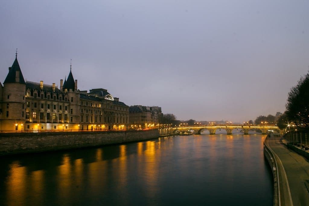 Serene dusk over the Seine River with historical Parisian architecture and bridge reflections.
